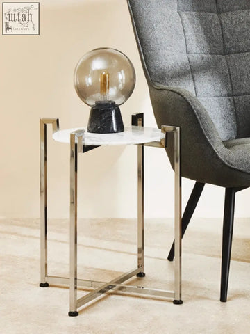 A sleek cibal white marble side table with grey veining and polished chrome legs perfect for modern spaces