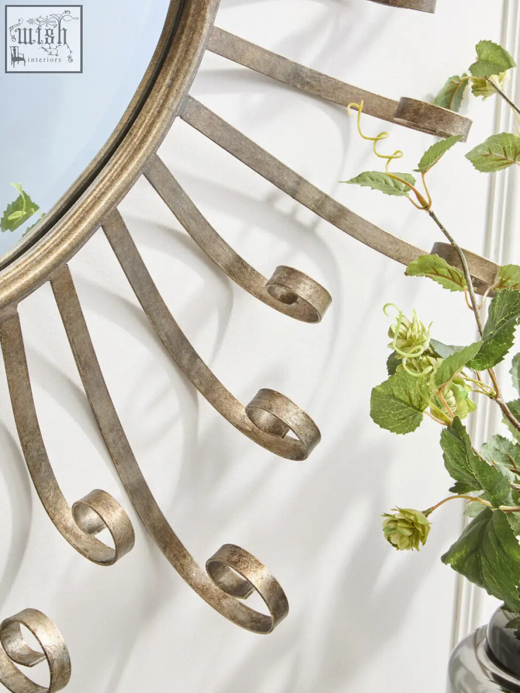 Antique brass cissell spoke style wall mirror with curved scrolled metal rays radiating from a circular frame