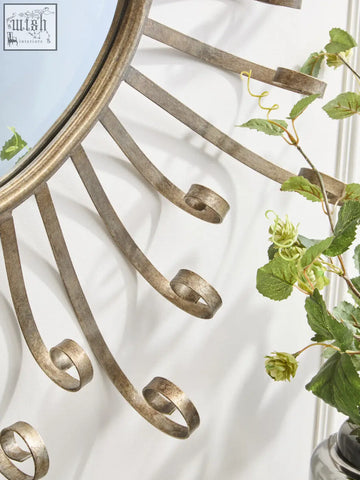 Antique brass cissell spoke style wall mirror with curved scrolled metal rays radiating from a circular frame