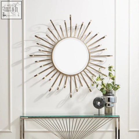 Cissell spoke style wall mirror with metallic gold sunburst frame and radiating rays on a white paneled wall