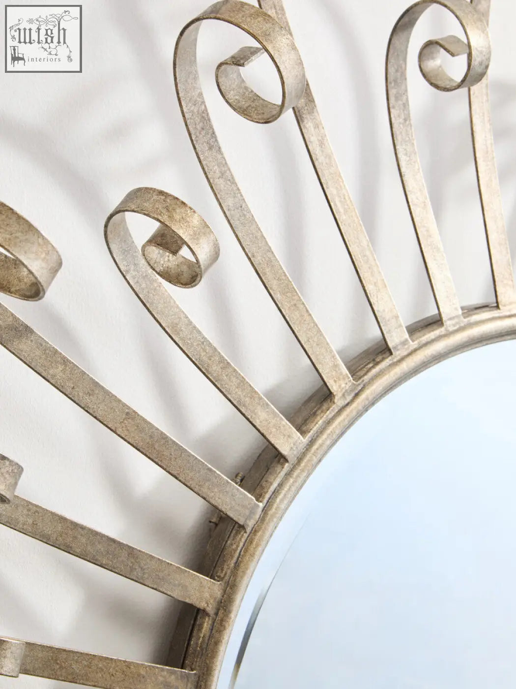 A cissell spoke style wall mirror featuring a sunburst design with a distressed silver ornate metal frame and scrollwork