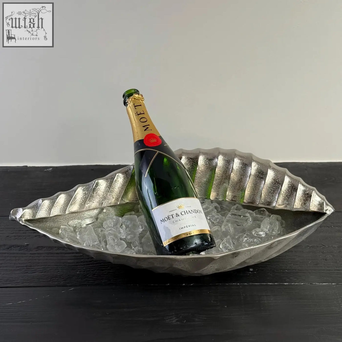 A silver clam shell solid cast ice bucket holding a bottle of moët & chandon champagne as a champagne ice bucket