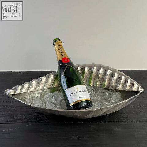 A silver clam shell solid cast ice bucket holding a bottle of moët & chandon champagne as a champagne ice bucket