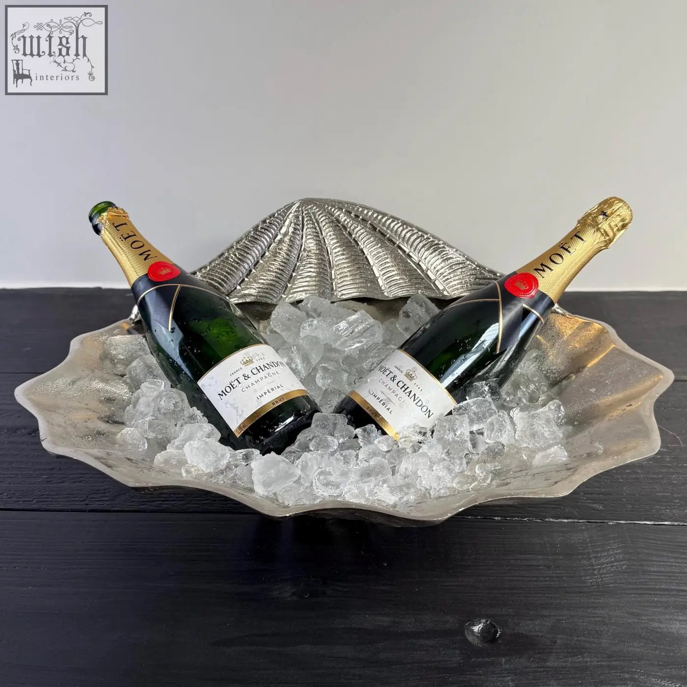Silver shell-shaped solid ice bucket holding two bottles of moët chandon champagne for chilling wine
