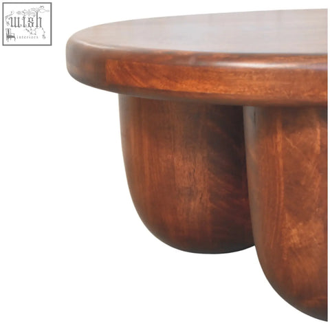 Rich warm-toned coffee table with smooth rounded top and sculptural legs made of solid mango wood oak