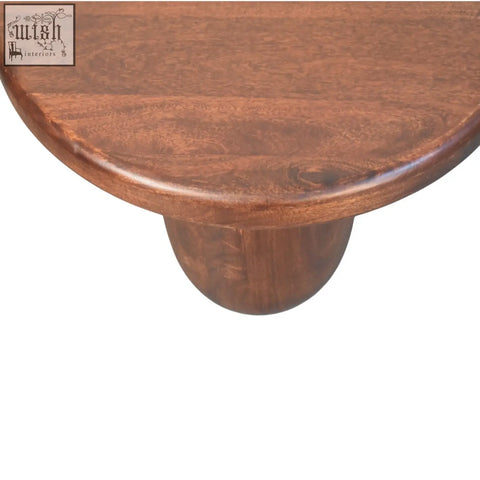 Clara sculpted coffee table with smooth rounded top in rich brown solid mango wood and visible natural grain