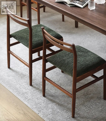 Two mid-century modern oak itao dining chairs with dark green upholstered seats perfect for dining areas