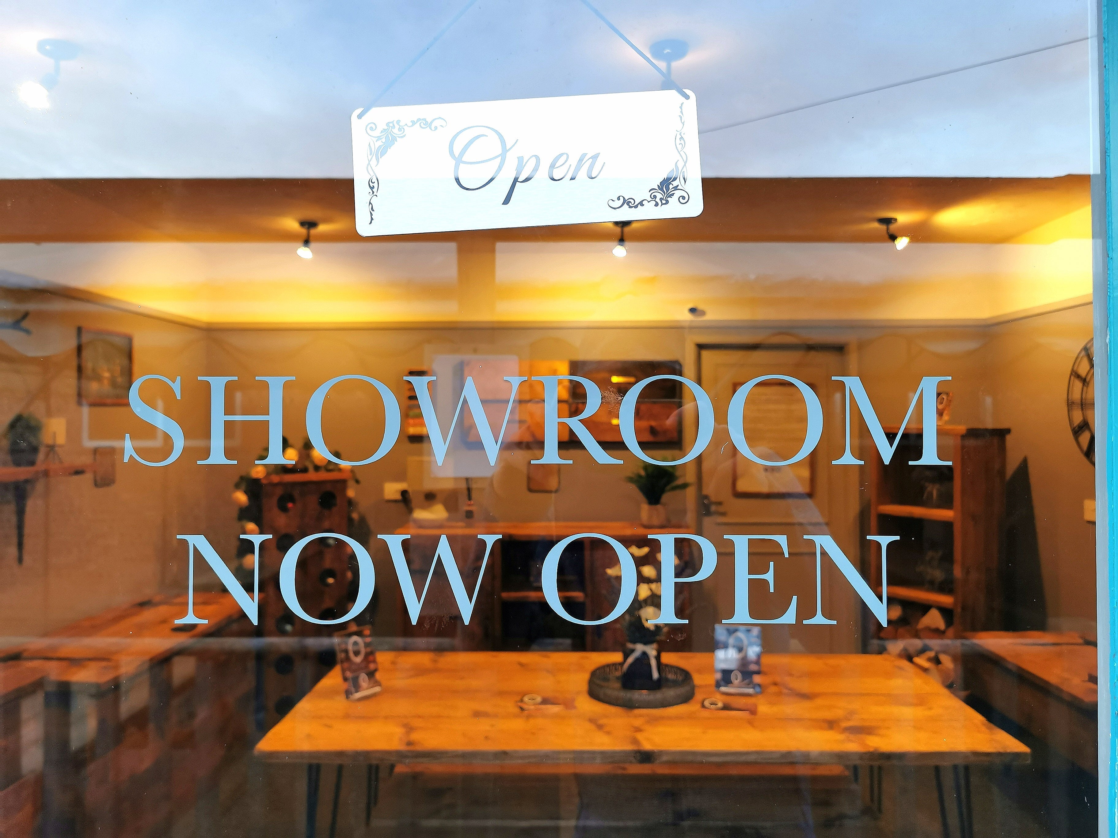 White rectangular open sign with black scrollwork mounted above glass storefront window for classic key bum decor