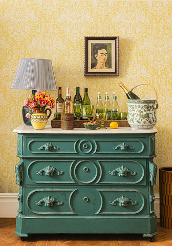 Teal green antique dresser with ornate handles and circular panels next to classic rattan trays set of 3