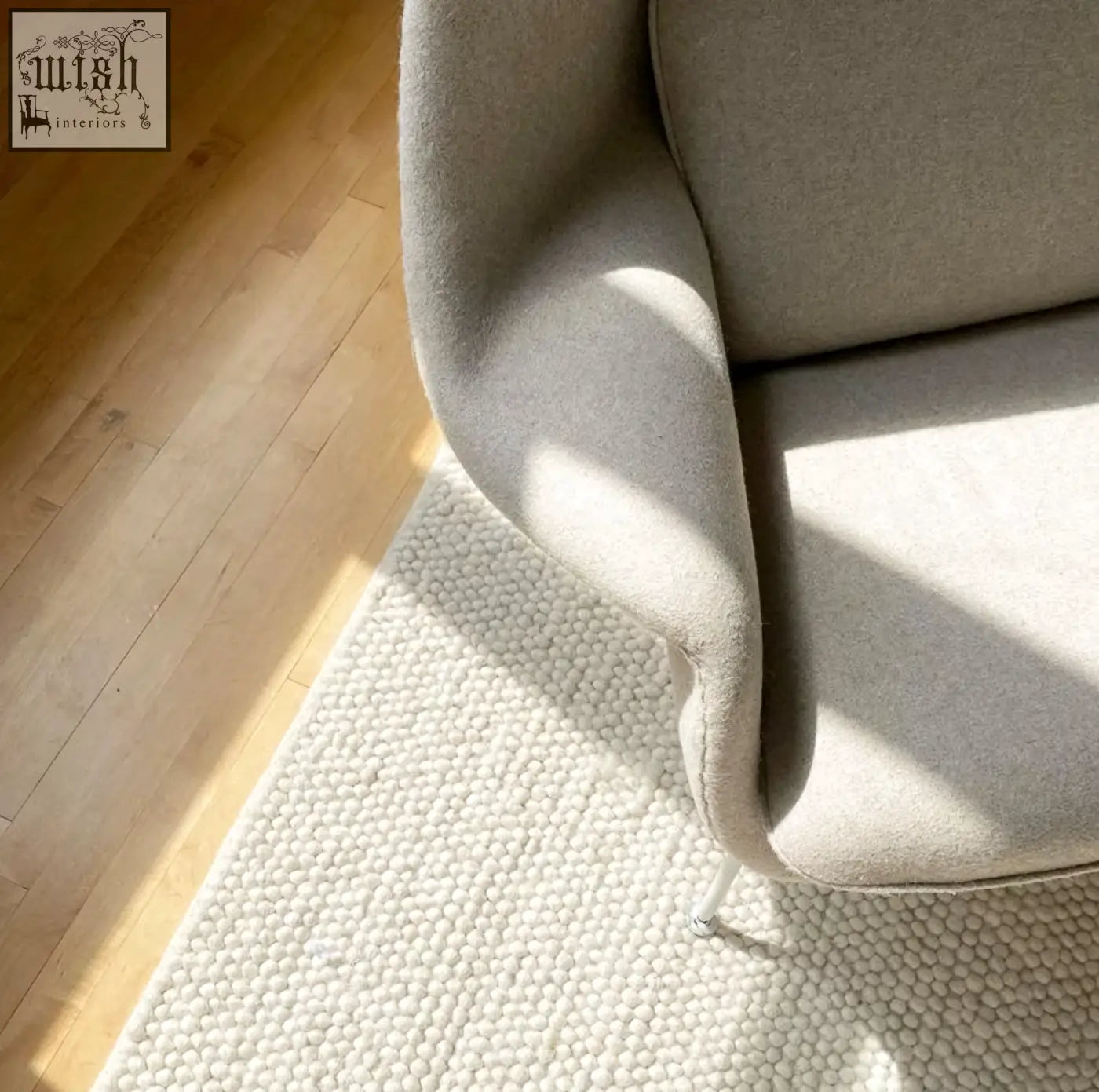 A sleek light gray classic womb chair upholstered in soft textured fabric with a minimalist design