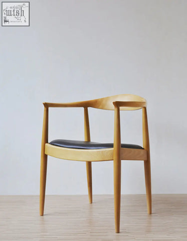 A minimalist classical kennedy dining chair in dark oak with a sleek curved wooden frame and black leather seat perfect for dining chairs