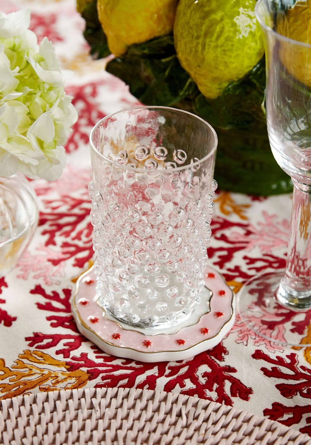 Clear dew drop tumblers set of 4 clear glass with textured bubble surface on pink ceramic coaster with red stars and gold trim