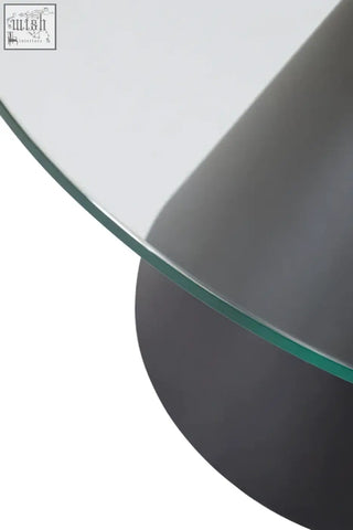 Clear glass round coffee table with sleek matte black cylindrical metal base perfect for modern living spaces