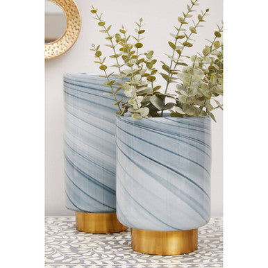 Two large grey glass vases with a marble effect and gold bases holding greenery perfect as a glass vase set