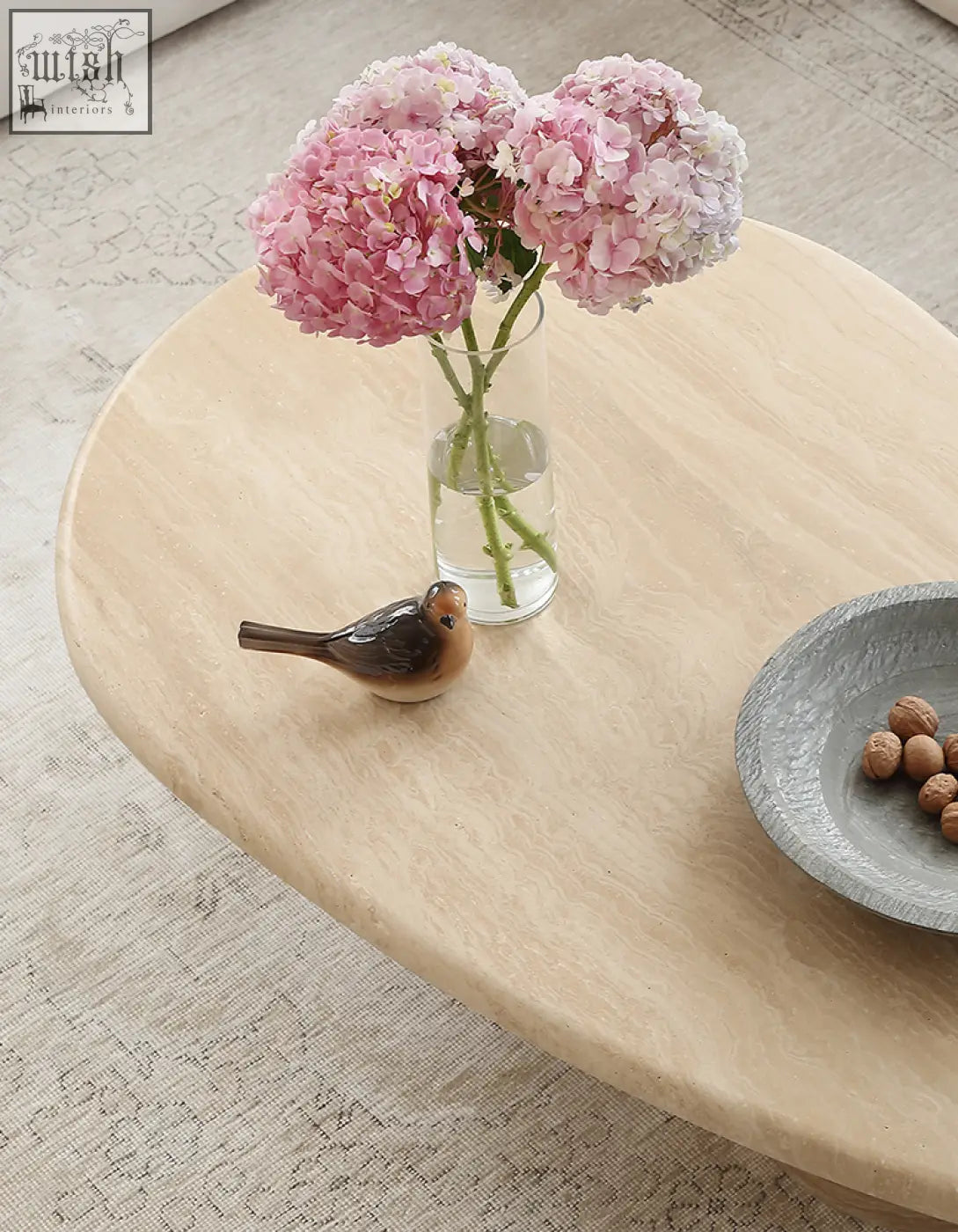 A clear glass vase with pink hydrangeas on a clio art deco oval coffee table with smooth curves and marble top