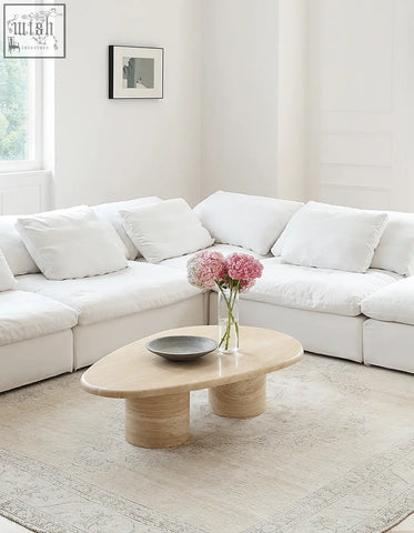 Light beige marble coffee table with smooth curves and an oval top supported by two cylindrical bases