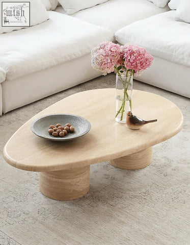Light beige marble coffee table with oval top and smooth curves featuring cylindrical pedestal legs for stylish living room use