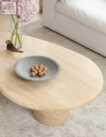 Clio art deco oval coffee table with light natural marble surface and smooth curves on a single cylindrical base