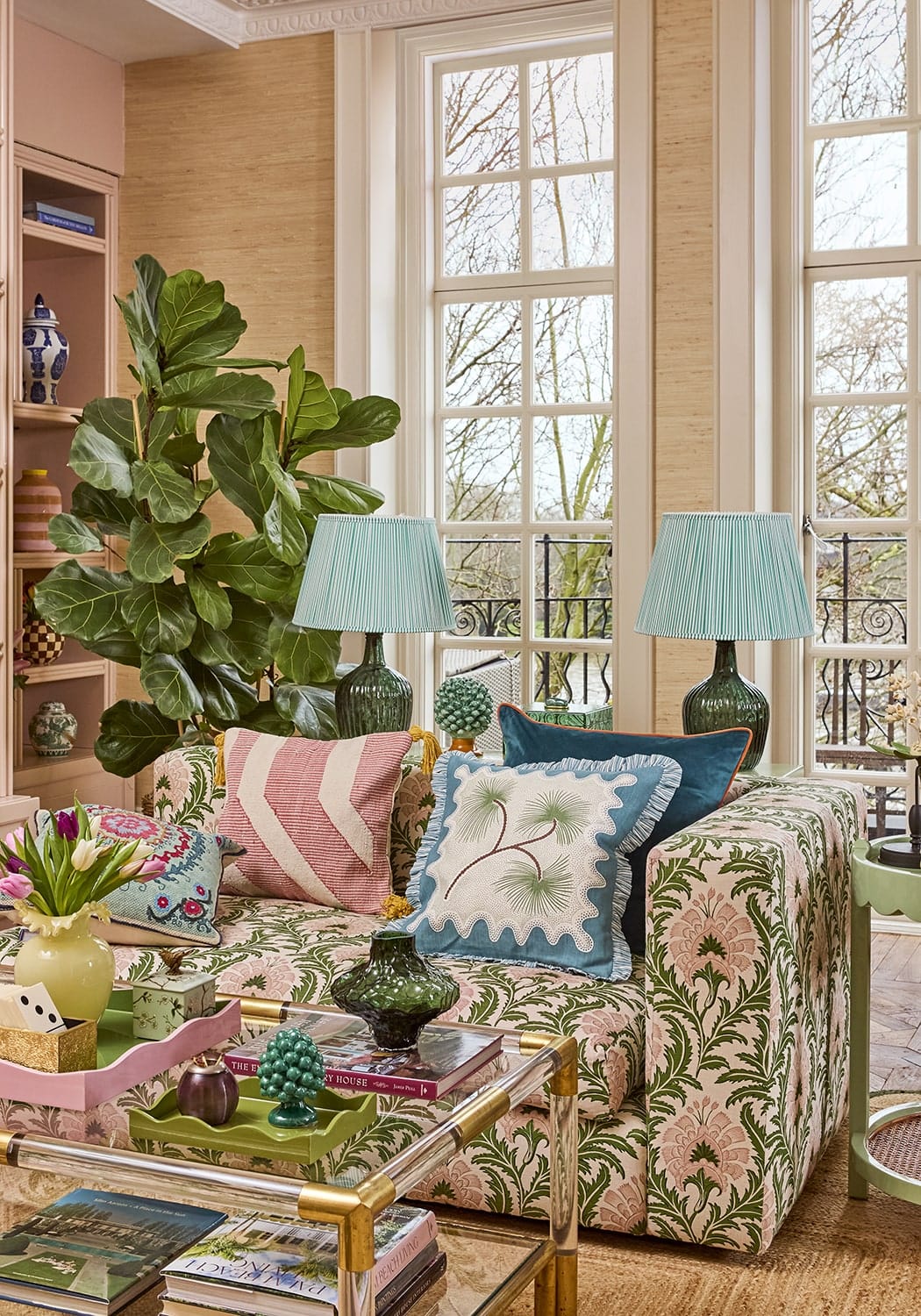 A floral-patterned coastal cabana cushion cover in soft pink and green fabric on a sofa with colorful throw pillows
