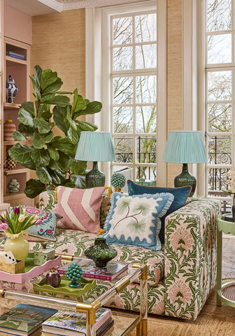 A floral-patterned coastal cabana cushion cover in soft pink and green fabric on a sofa with colorful throw pillows