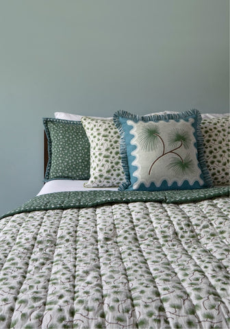 Coastal cabana cushion cover with white base green embroidered pine needles and teal fringed edges on a square pillow