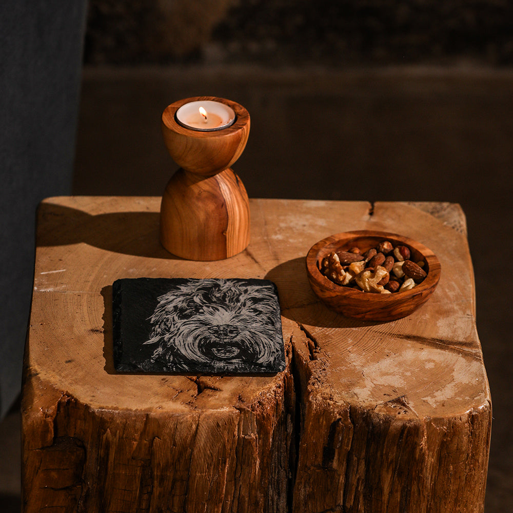 A rustic olive wood candle holder with polished finish and natural grain paired with a cockapoo single slate coaster