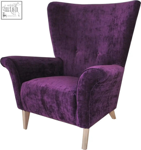 A plush deep purple velvet coco wing chair with a high back and solid beech curved wooden legs