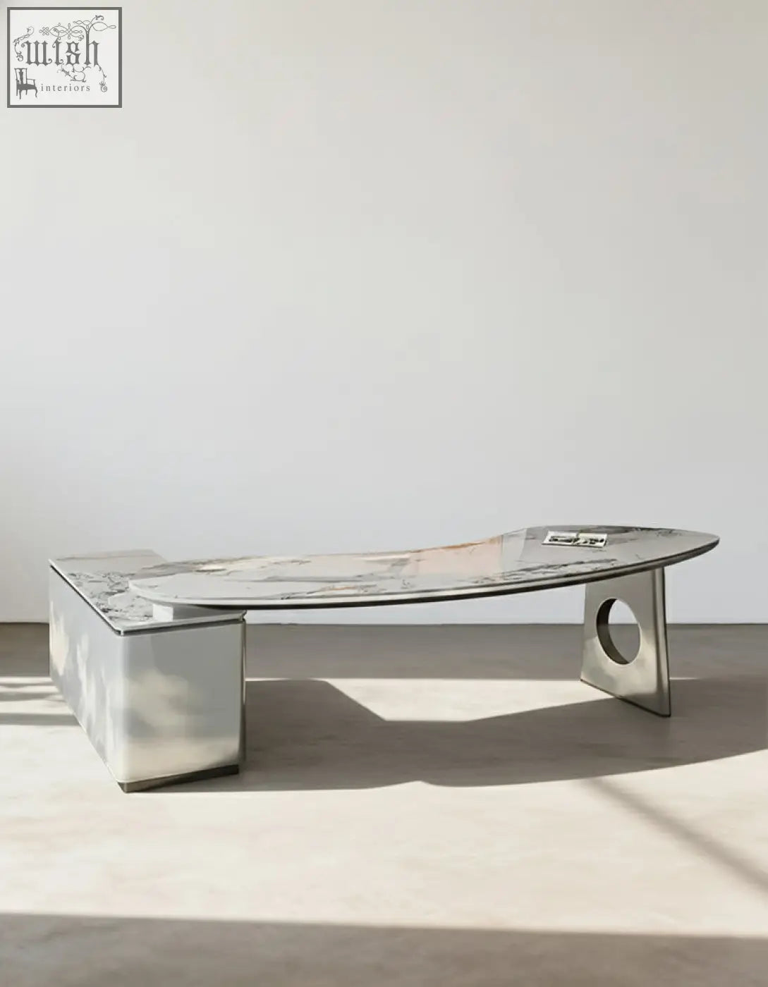 Modern metallic coffee table with curved glass top and angular legs paired with coelho corner office desk sintered stone