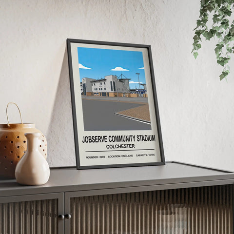 Black-framed poster of jobserve community stadium in colchester with stylized illustration and key stadium details