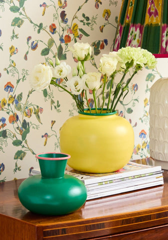 Bright yellow ceramic vase with green rim holding white flowers perfect for colorful home decor