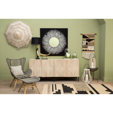 Beige woven macrame wall hanging with circular textured design paired with concrete bowl shaped side table