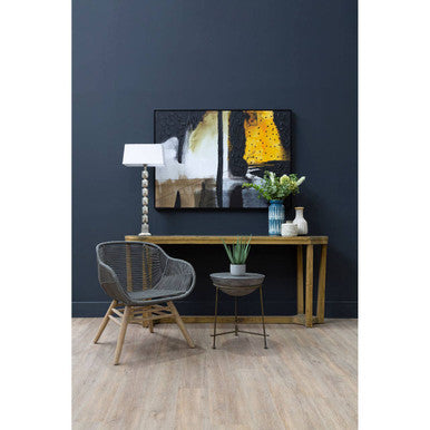Black and yellow abstract painting above Compo concrete bowl shaped side table on dark navy wall with antique silver accents