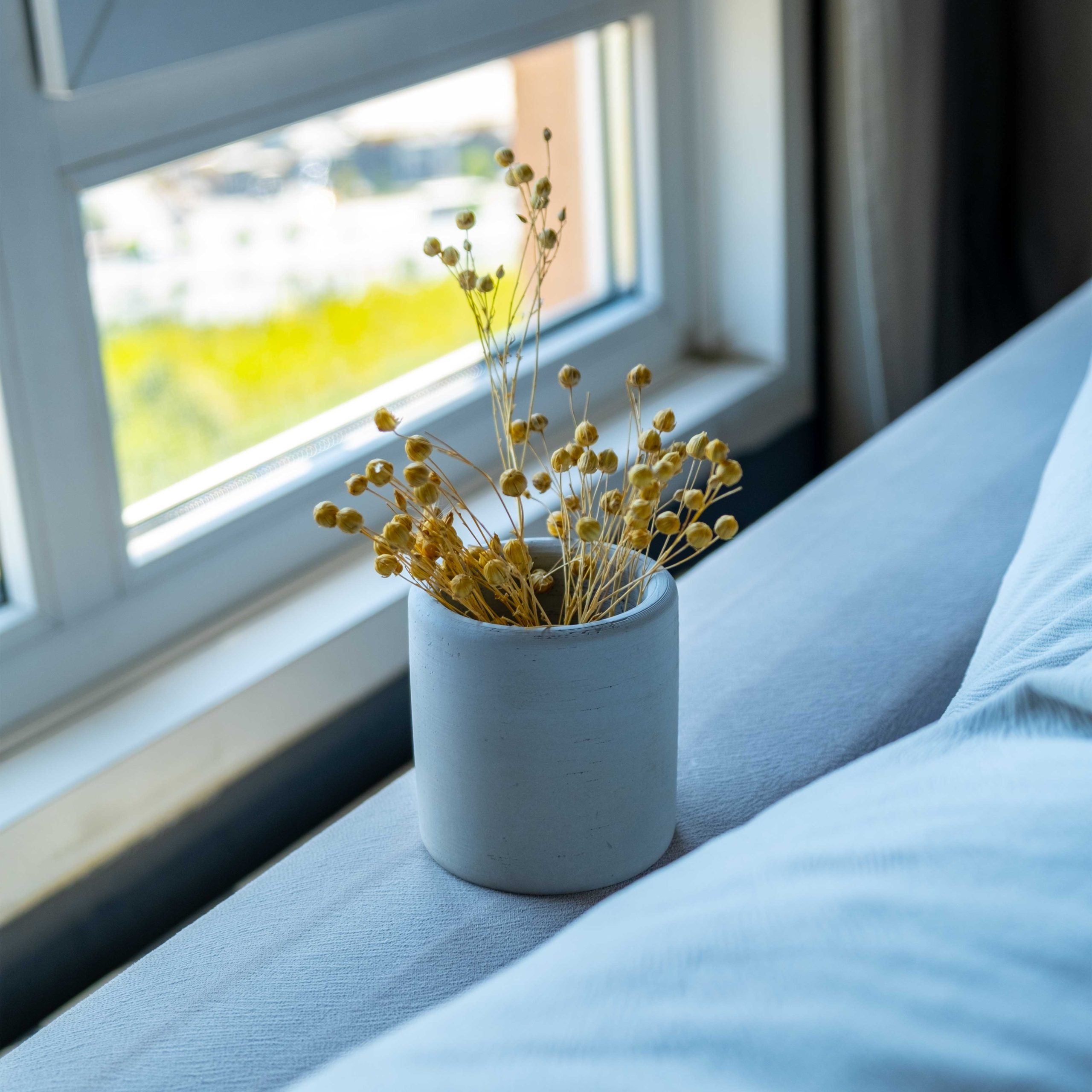 Minimalist white ceramic vase with dried yellow flowers displayed inside a concrete pen-pencil holder accessory