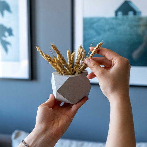 White concrete polygonal pot with geometric design holding dried wheat stalks for minimalist decor