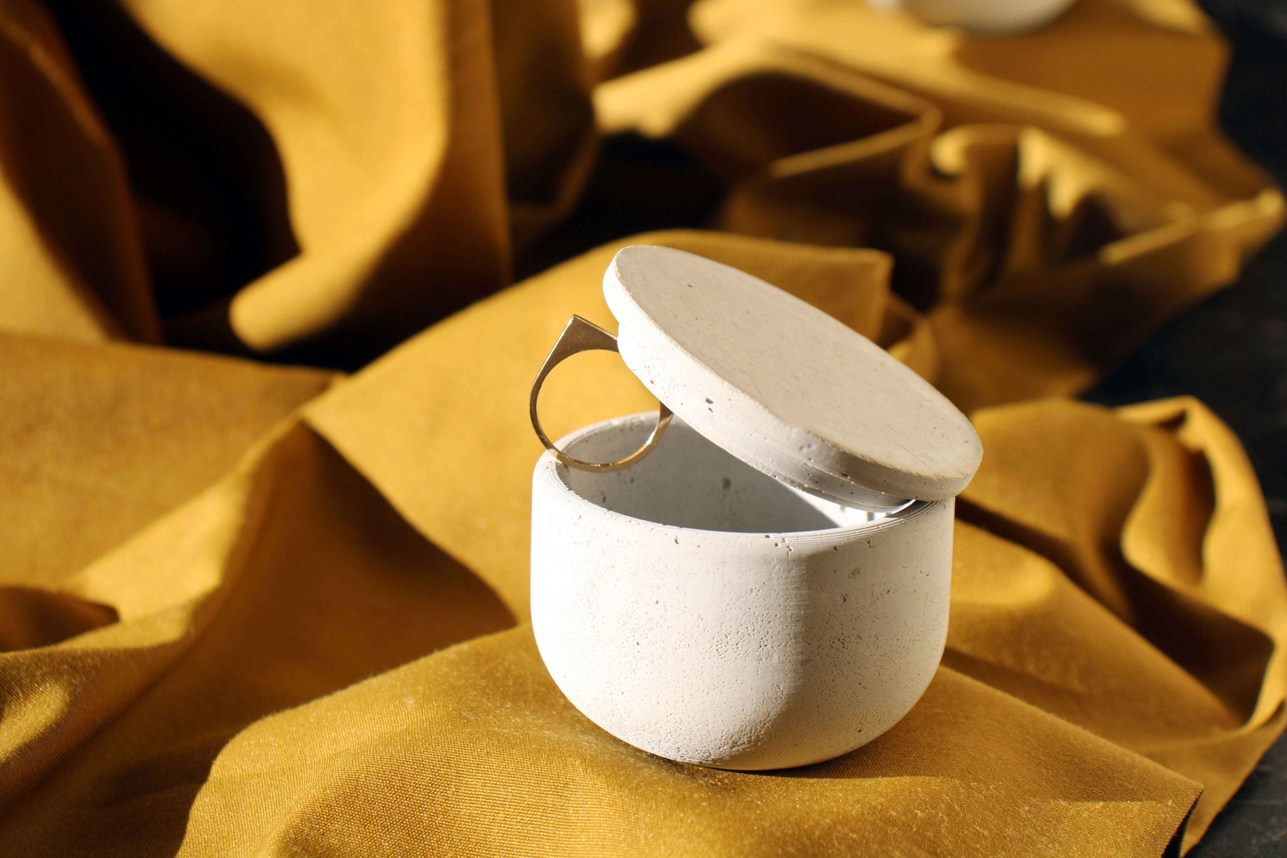 White speckled ceramic concrete small jewellery holder with matching lid open showing gold ring inside, candle holder style