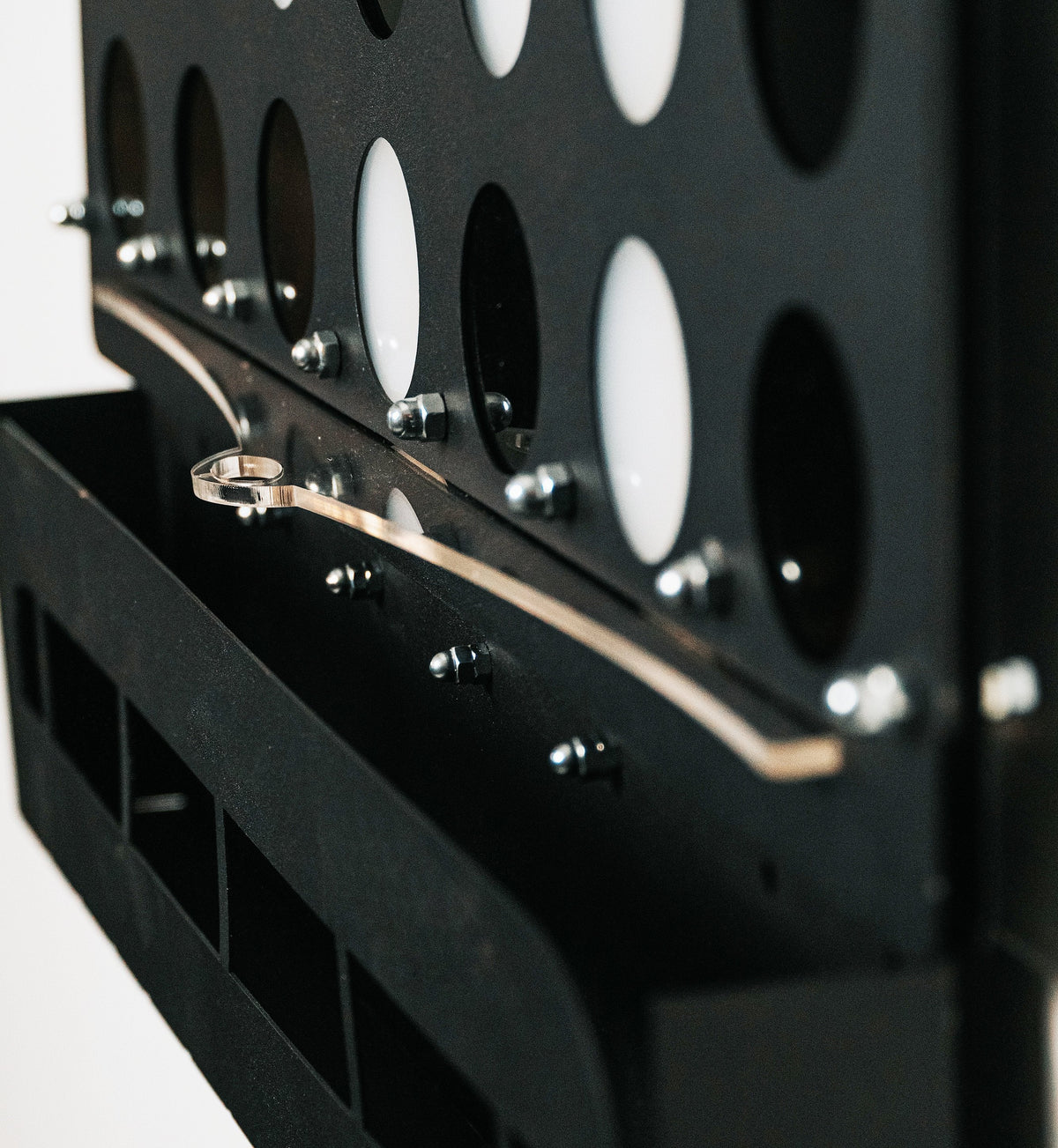 Black metal connect 4 game board with circular holes and silver lever stopper piece for game control