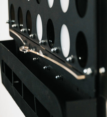 Black metal connect 4 game board with circular holes and silver lever stopper piece for game control