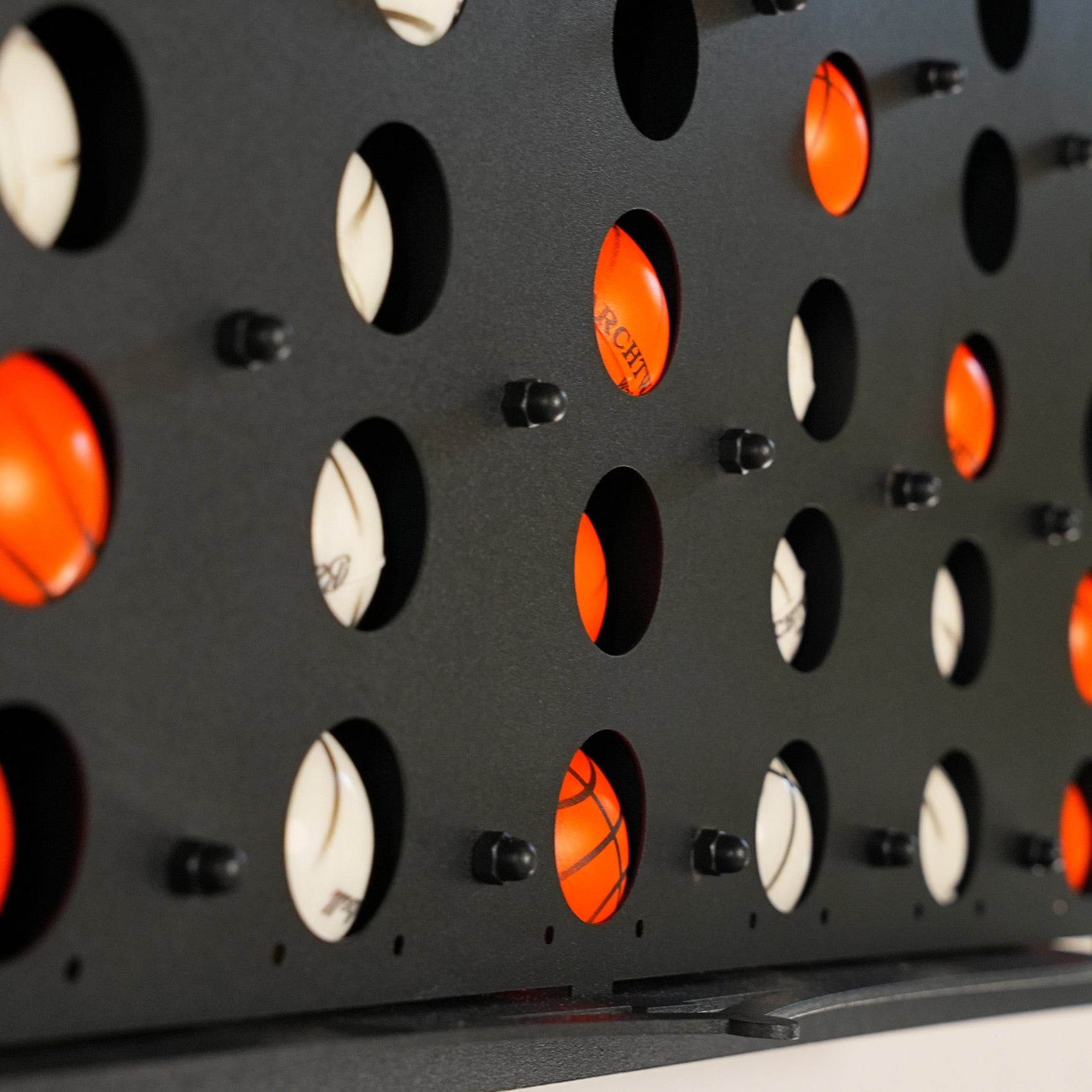 Black metal grid connect balls wall game board with orange and white four balls in circular holes and central piece