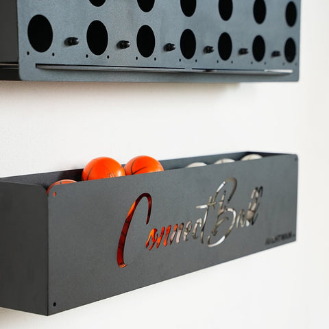 Black metal wall-mounted basketball storage tray with connect balls engraved in silver as central piece for four balls