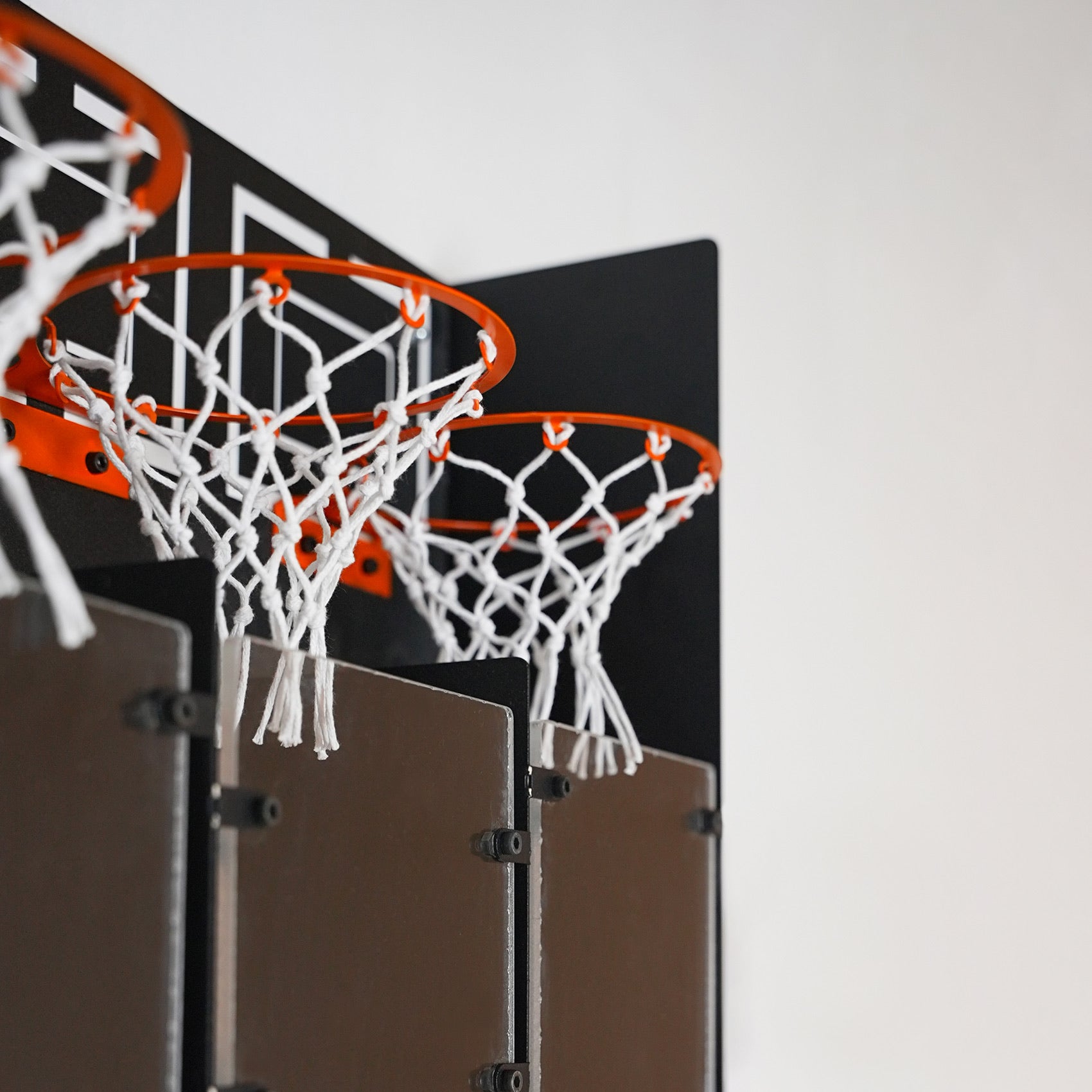 Orange basketball hoops with white nets on a black backboard in connectballs wall game featuring a central piece