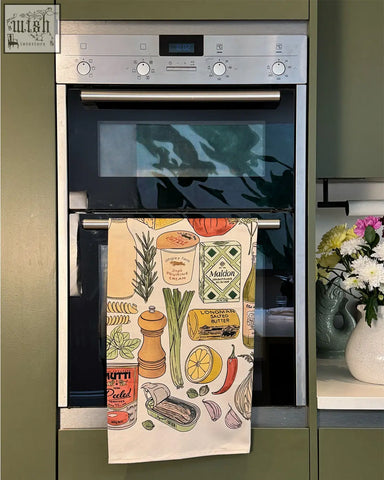A cream cooking essentials tea towel with colorful illustrated butter herbs and spices pattern for kitchen use