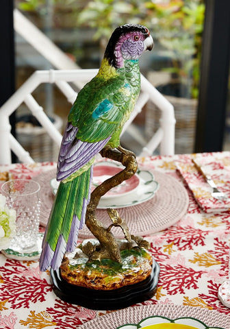 Vibrant green and purple ceramic parrot figurine perched on a detailed branch called copacabana the hottest bird north of havana
