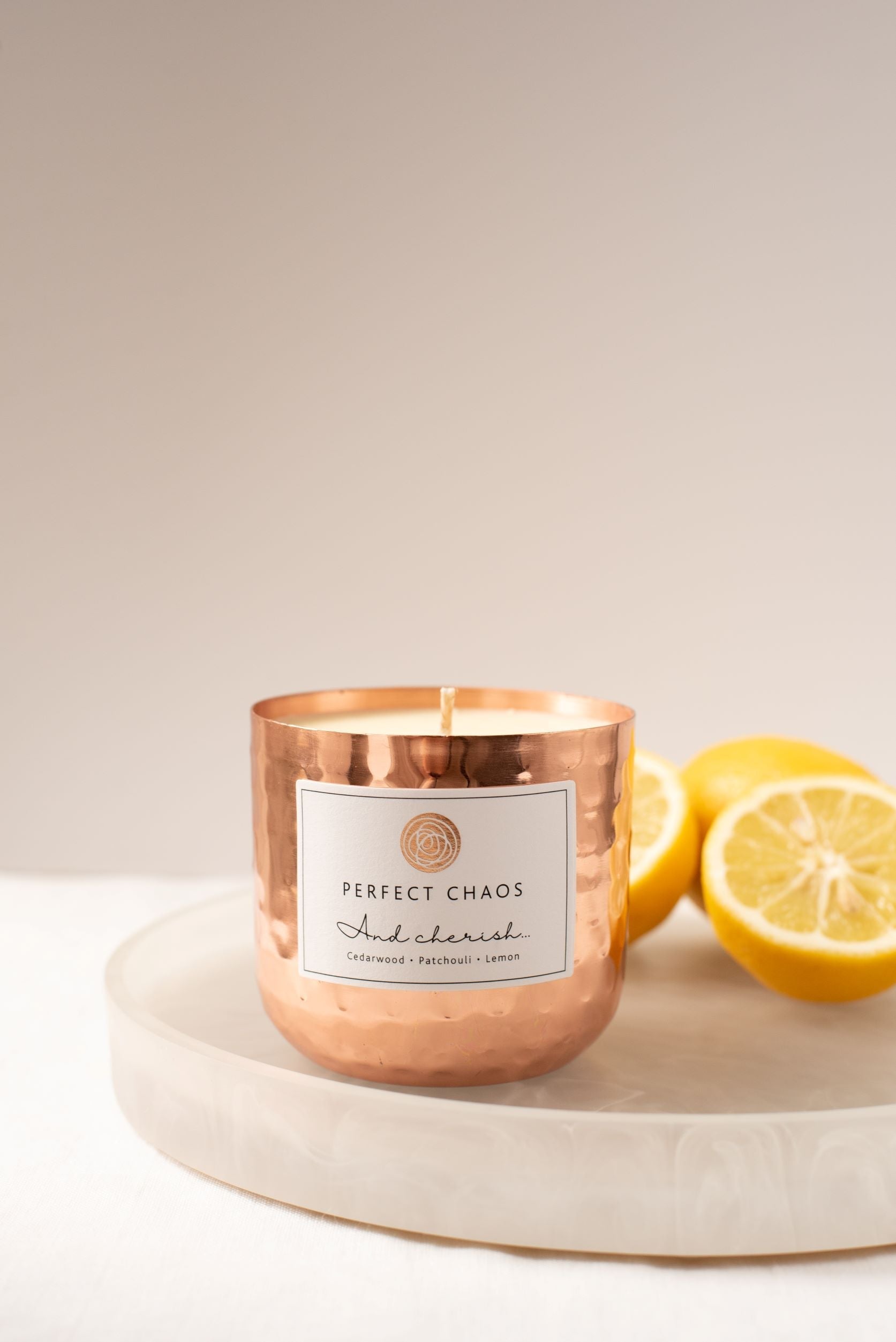 Copper dimpled candle in hammered copper vessel with perfect chaos label featuring cedarwood patchouli and lemon essential oils