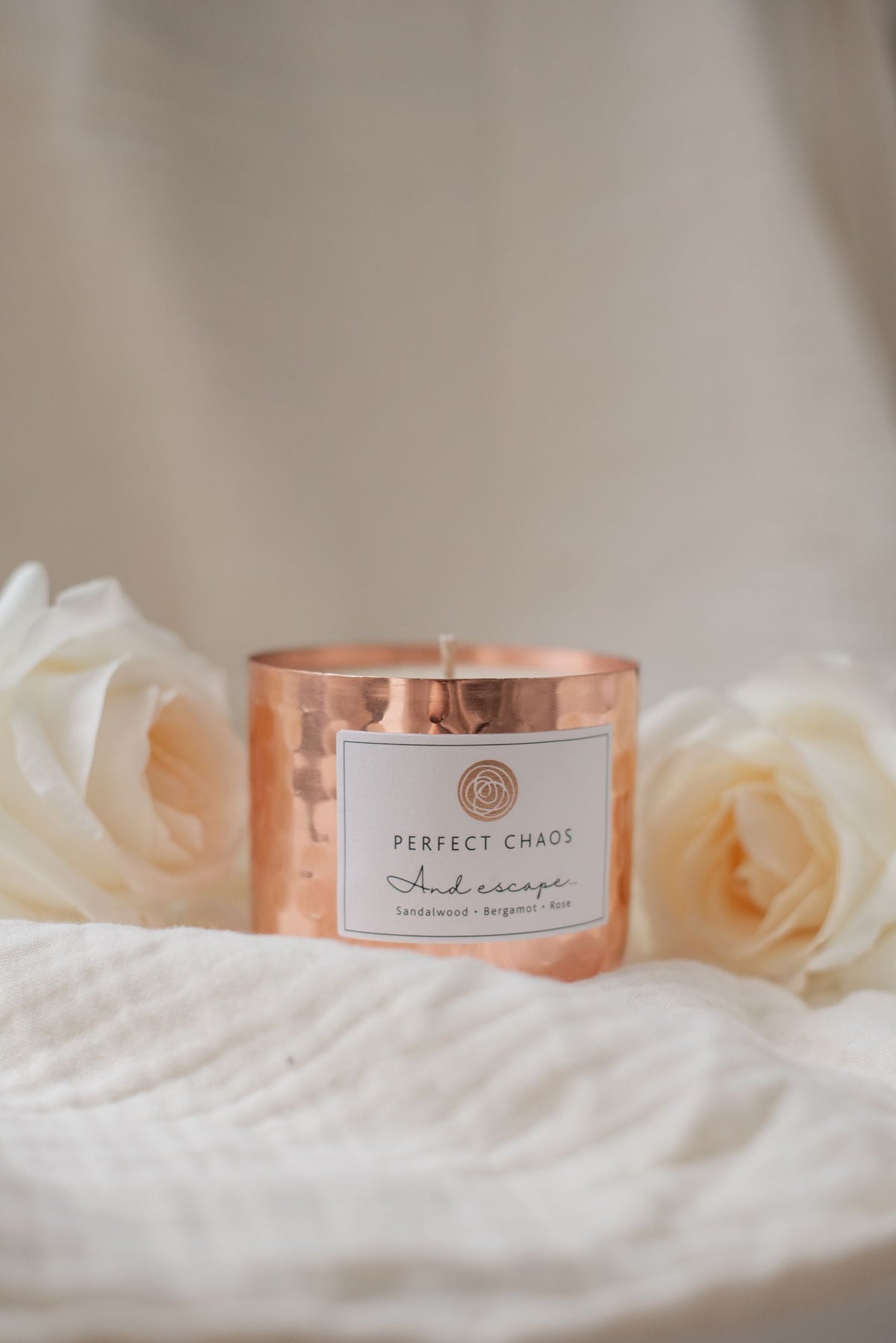 Copper dimpled candle in hammered metal container with perfect chaos and escape label scented with sandalwood bergamot and rose