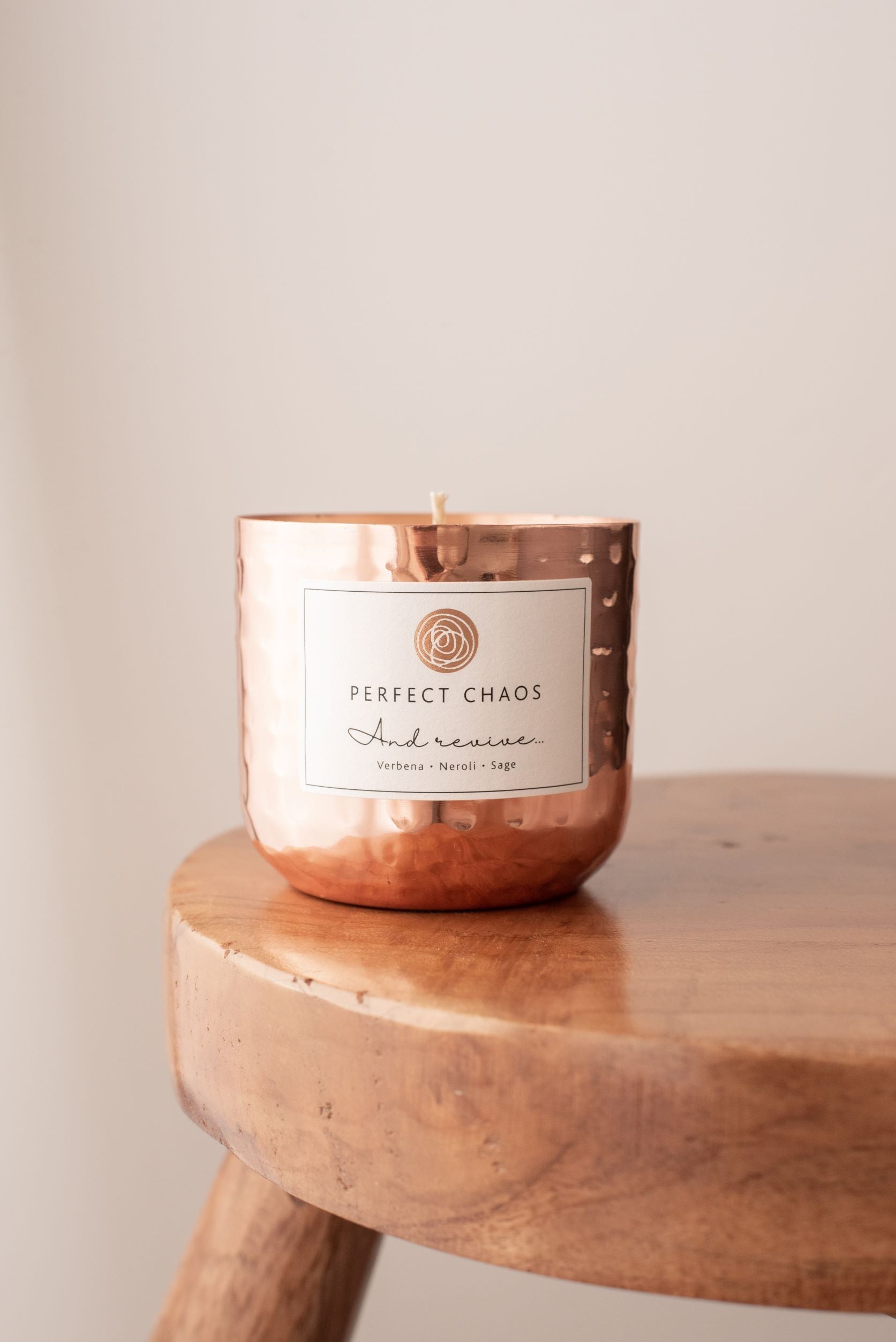 Copper dimpled candle jar with hammered texture and perfect chaos label scented with essential oils of verbena neroli sage