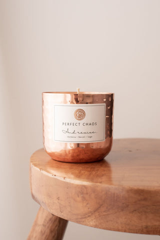 Copper dimpled candle jar with hammered texture and perfect chaos label scented with essential oils of verbena neroli sage