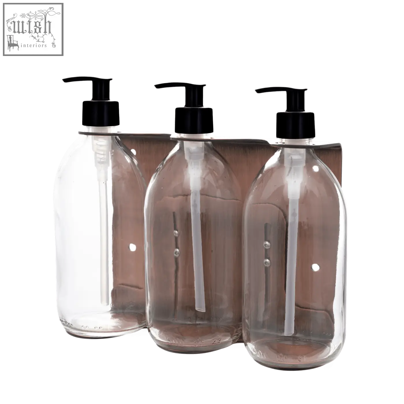 Three clear plastic bottles with black pumps in a copper triple wall-mounted soap dispenser on wooden rack