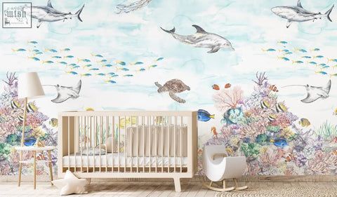 Light wood crib with white bedding in front of coral reef mural wallpaper by artist katie for nursery decor