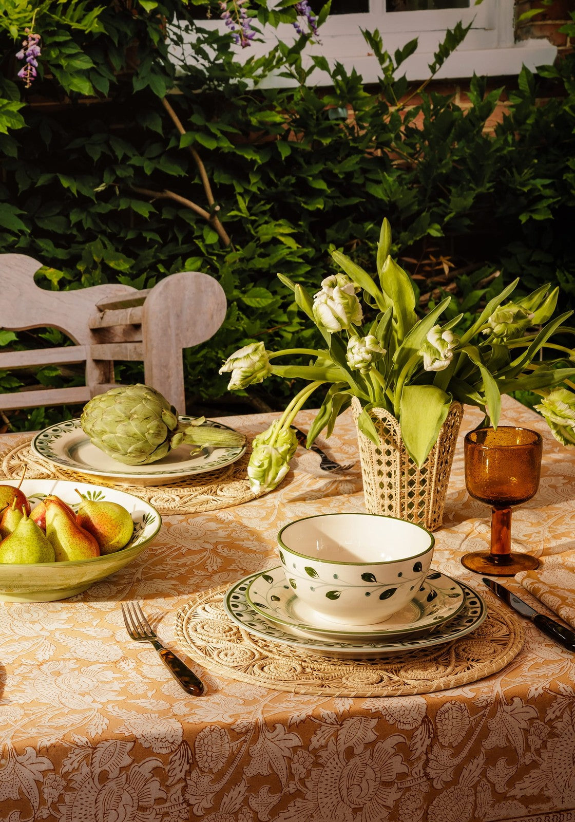 White ceramic cordelia dinner plate in green with leaf patterns on a matching saucer over a lace placemat