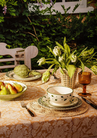 White ceramic cordelia dinner plate in green with leaf patterns on a matching saucer over a lace placemat